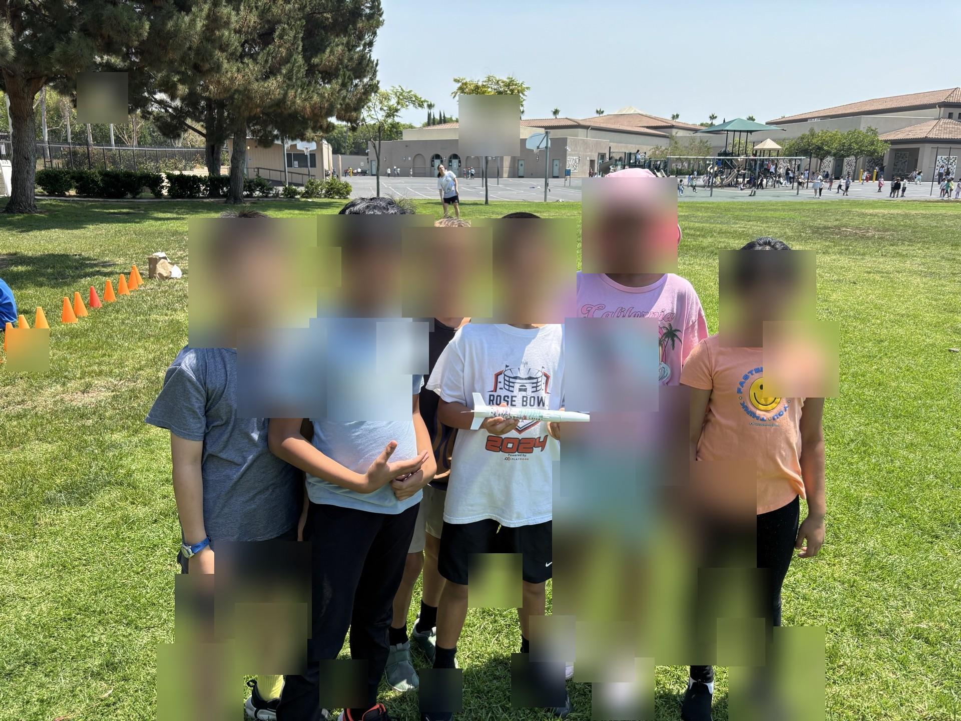 Students posing with their rocket on the field